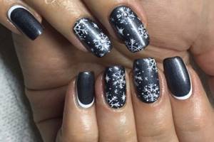 Black polish as a background for a manicure with snowflakes