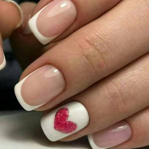 A beautiful French manicure for short nails with a design on the ring nail - a heart with sparkles.