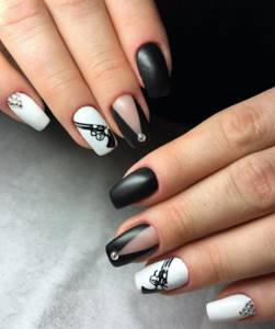 Manicure in black and white with rhinestones and patterns.