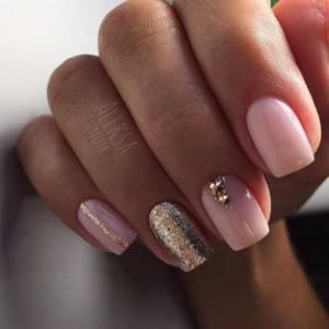 Delicate nude manicure with an accent on the middle finger in the form of gold rhinestones, on the ring finger there are sparkles, and on the little finger there is a gold stripe.