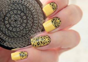 Yellow manicure with black ethnic pattern made from stamps